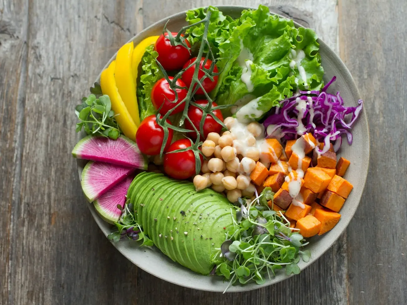 Tigela com folhas, legumes, grãos e abacate